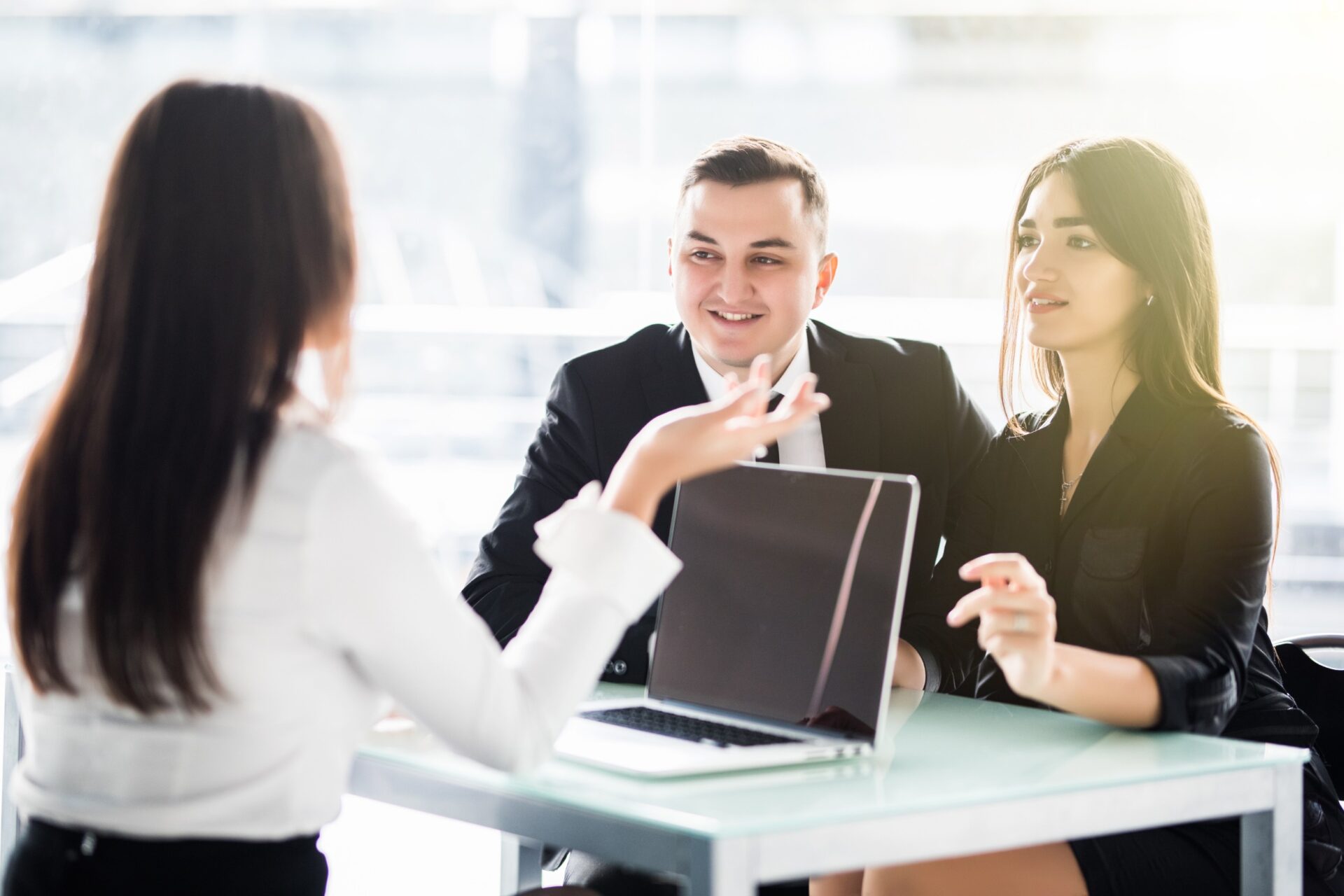 Young couple sitting at a desk in the office of their adviser discussing about accounting